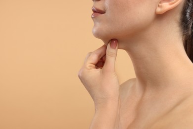 Photo of Woman touching her chin on beige background, closeup. Space for text