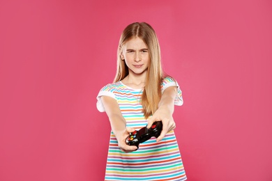 Teenage girl playing video games with controller on color background