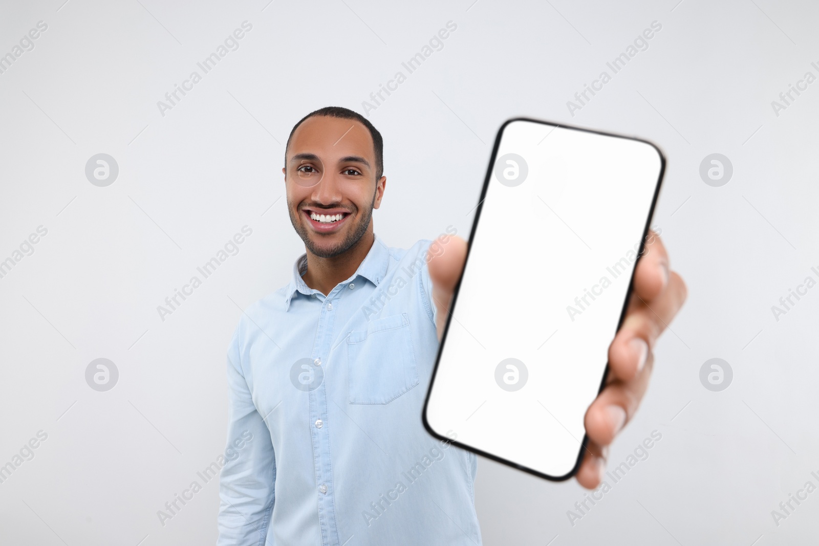 Photo of Young man showing smartphone in hand on white background