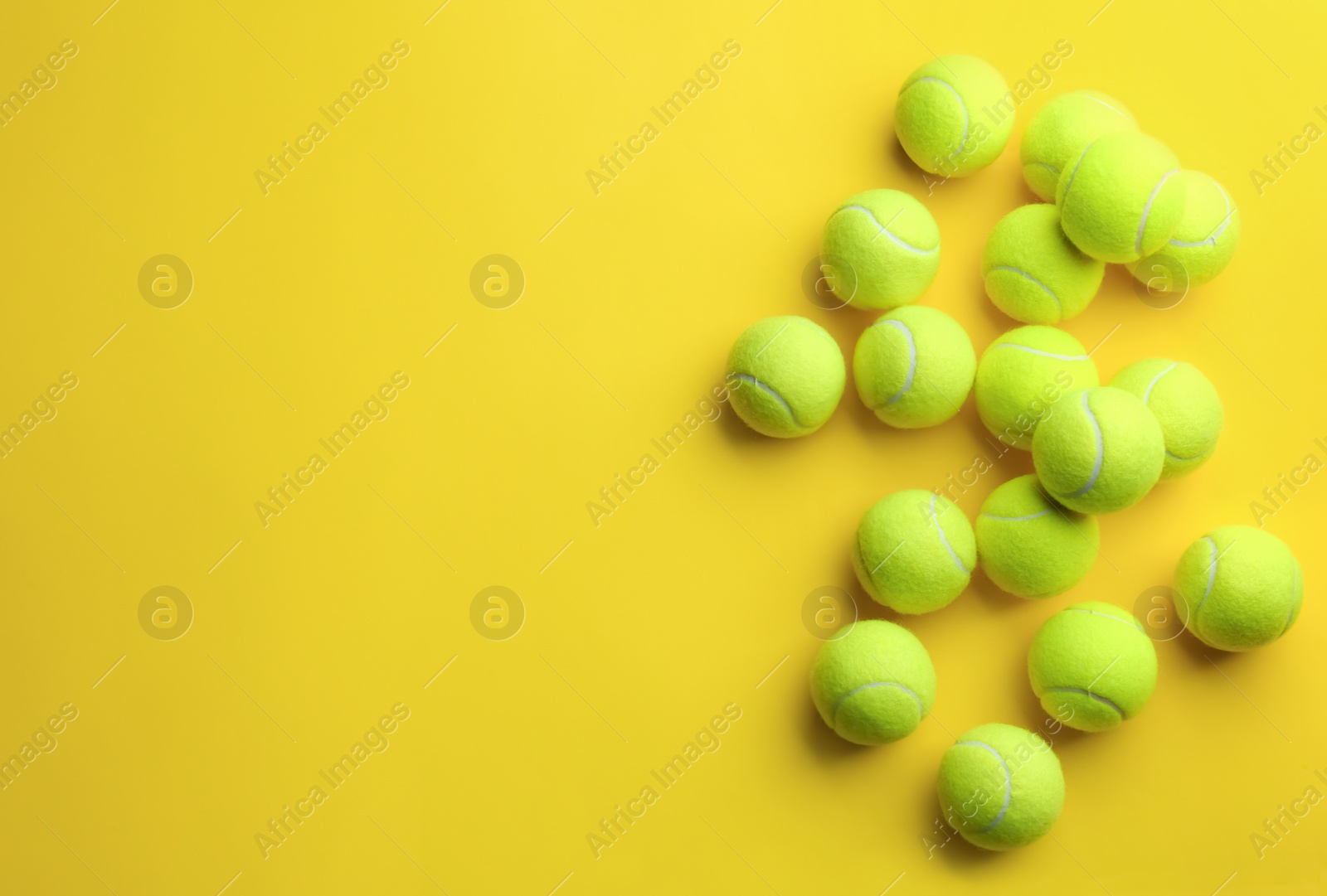 Photo of Tennis balls on yellow background, flat lay. Space for text