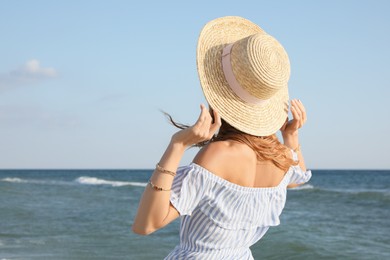 Photo of Woman with straw hat near sea on sunny day