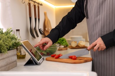 Man using tablet while cooking at countertop in kitchen, closeup