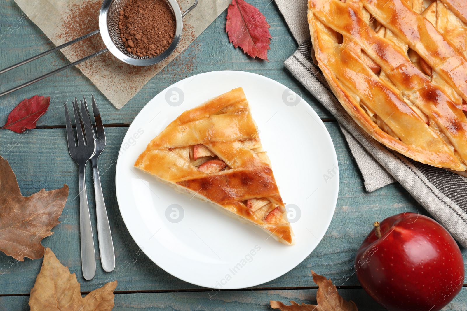 Photo of Slice of traditional apple pie served on blue wooden table, flat lay