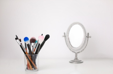 Holder with makeup brushes on table