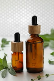 Photo of Bottles of essential oils and fresh herbs on white table