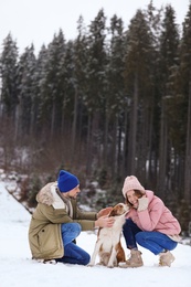 Couple with dog near forest, space for text. Winter vacation