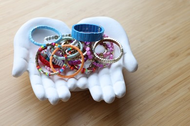 Ceramic hand stand with many stylish bracelets on wooden table