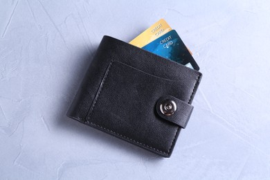 Credit cards in leather wallet on grey textured table, top view