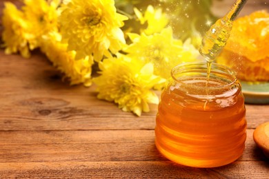 Natural honey in glass jar and dipper on wooden table under sunlight, space for text