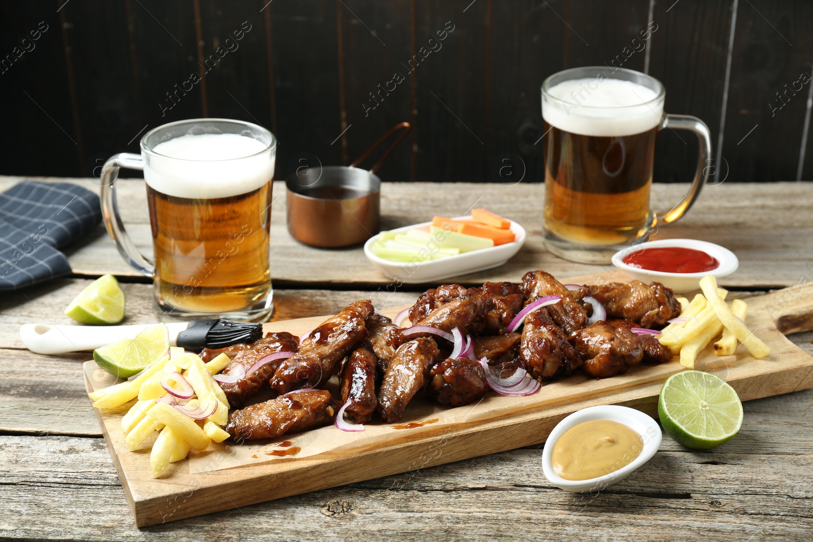 Photo of Tasty roasted chicken wings served with beer on wooden table