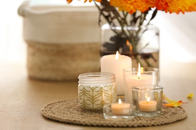 Beautiful burning candles, bag and flowers on table at home