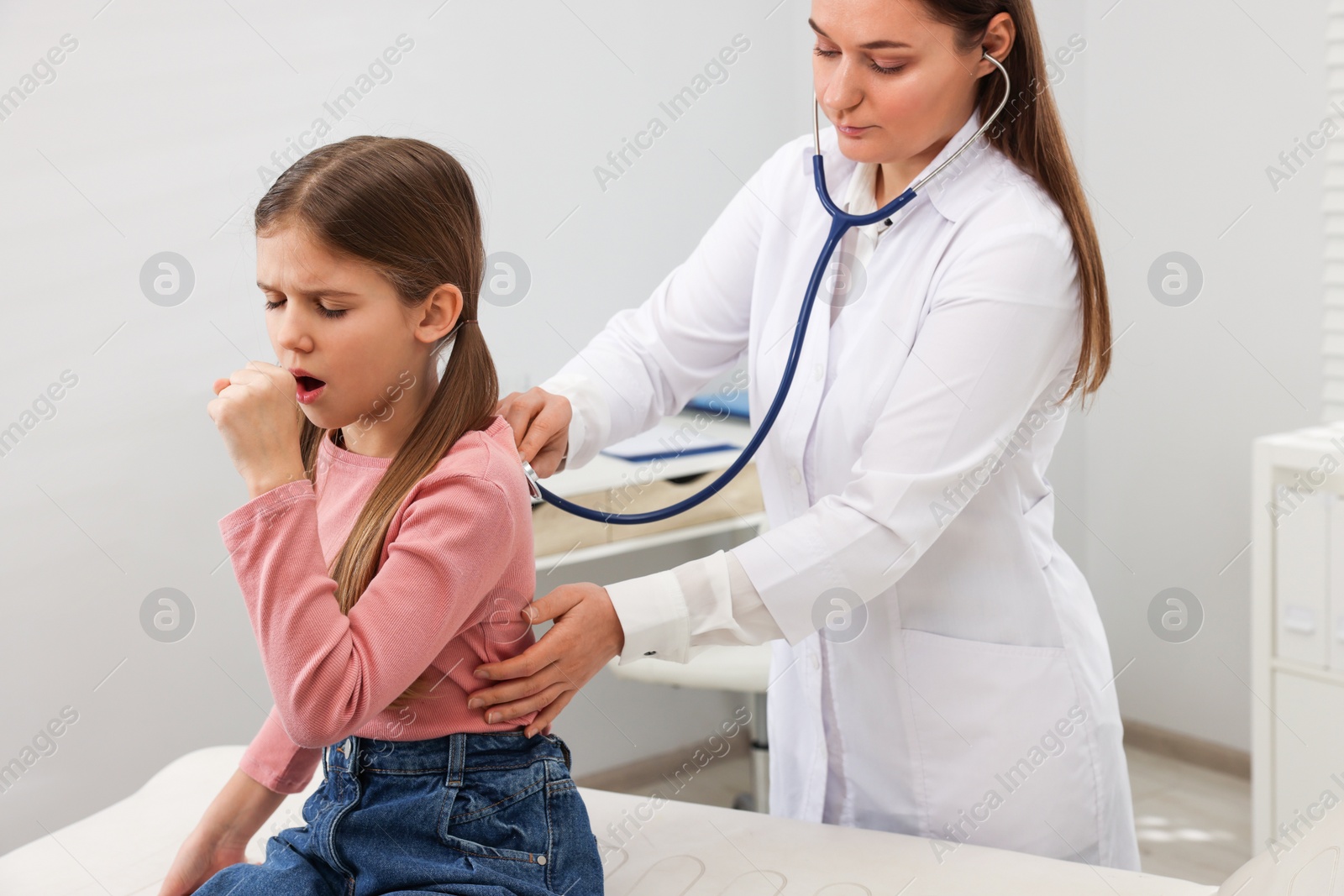 Photo of Doctor examining coughing girl in hospital. Cold symptoms