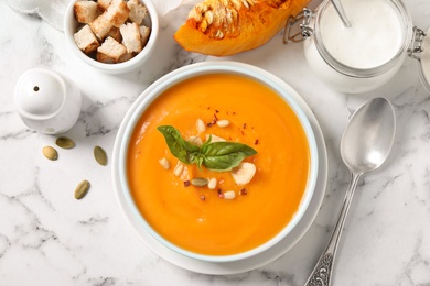 Photo of Delicious pumpkin soup in bowl on marble table, flat lay