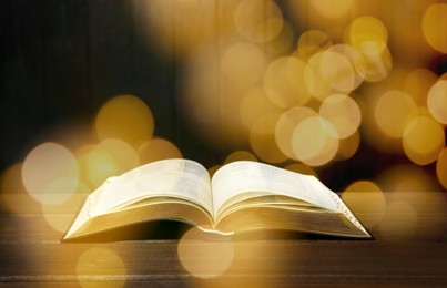 Image of Open Bible on wooden table, bokeh effect