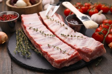 Photo of Fresh raw pork ribs with thyme on wooden table, closeup