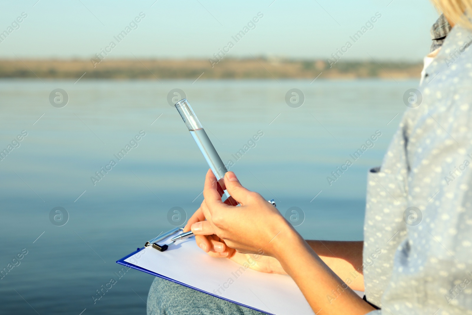 Photo of Scientist with clipboard and sample taken from river, closeup