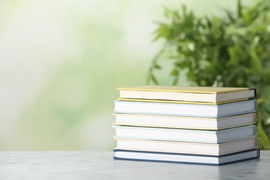 Photo of Stack of hardcover books on table against blurred background, space for text