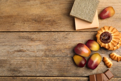 Fresh ripe palm oil fruits, sweets and cosmetic products on wooden table, flat lay. Space for text