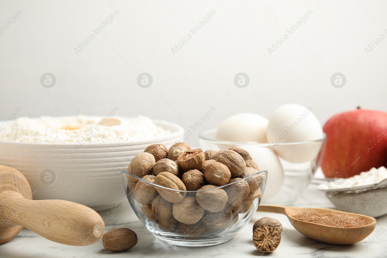 Photo of Nutmeg seeds and other ingredients for pastry on white marble table