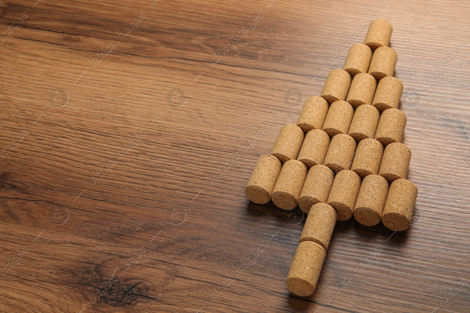 Photo of Christmas tree made of wine corks on wooden table. Space for text