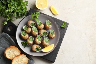 Photo of Delicious cooked snails served on light table, flat lay. Space for text