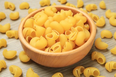 Photo of Raw macaroni pasta on wooden table, closeup