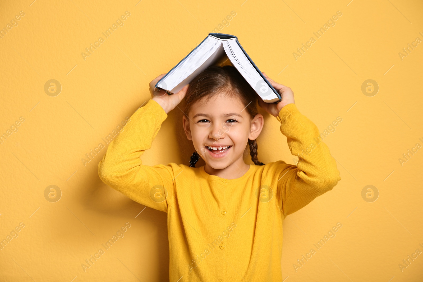 Photo of Cute little girl with book on color background