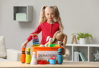 Cute little girl sorting donation box at home