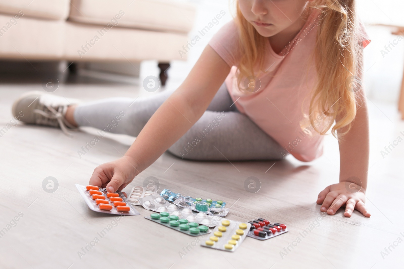 Photo of Little child with different pills on floor at home. Household danger