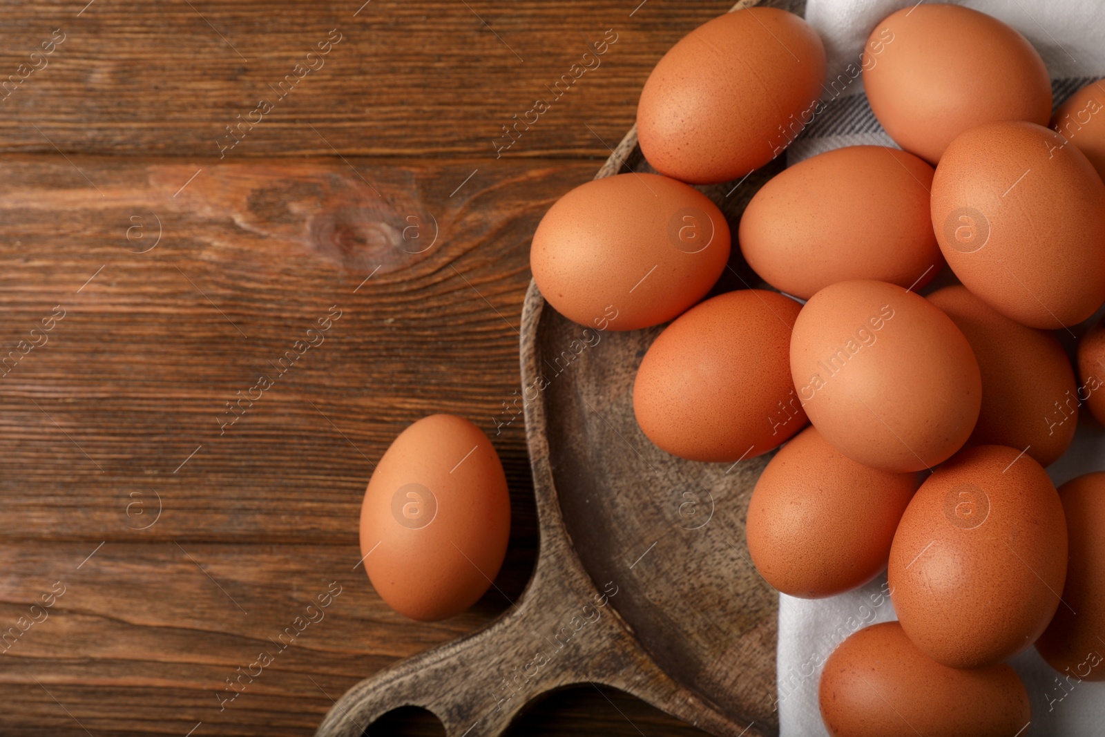 Photo of Raw brown chicken eggs on wooden table, flat lay. Space for text