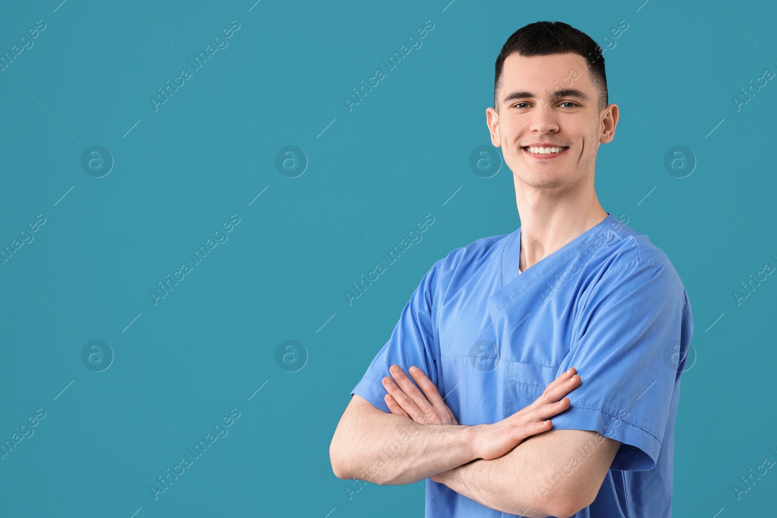 Photo of Portrait of smiling medical assistant with crossed arms on light blue background. Space for text