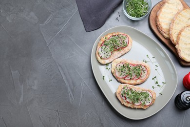 Delicious sandwiches with radish, cheese and microgreens on grey table, flat lay. Space for text
