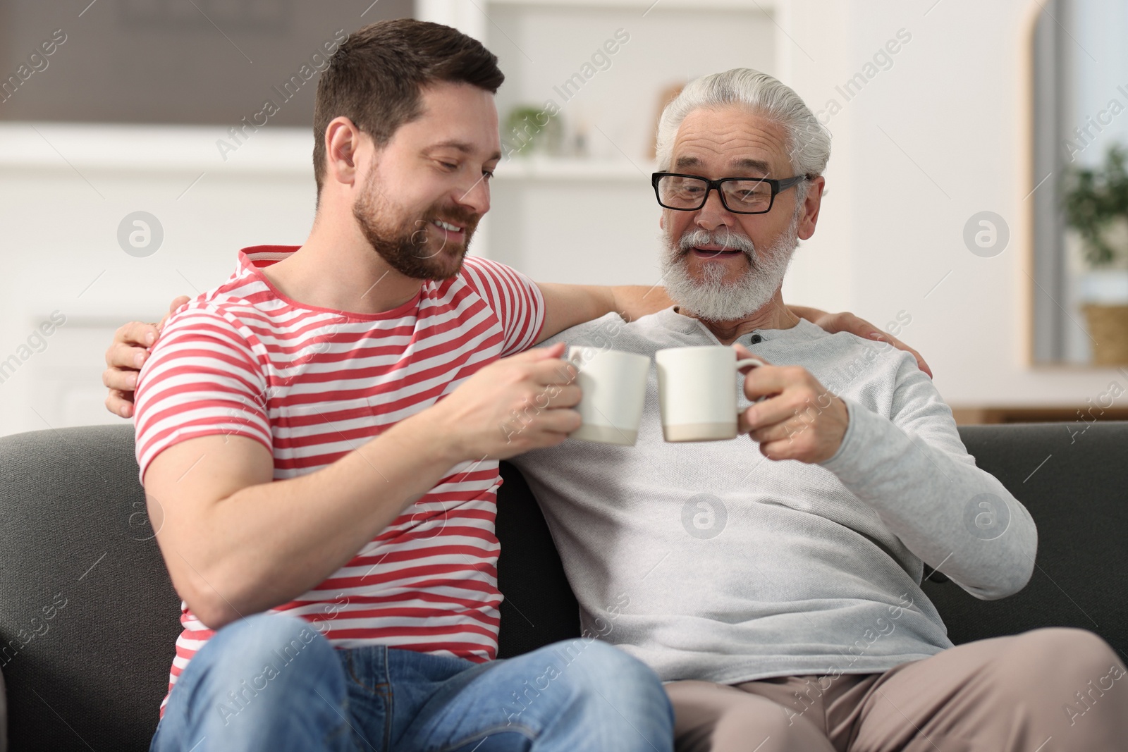 Photo of Happy son and his dad with cups at home