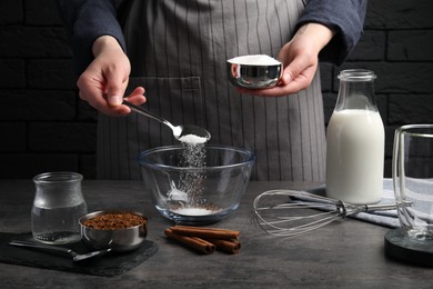 Photo of Making dalgona coffee. Woman pouring sugar into bowl at grey table, closeup
