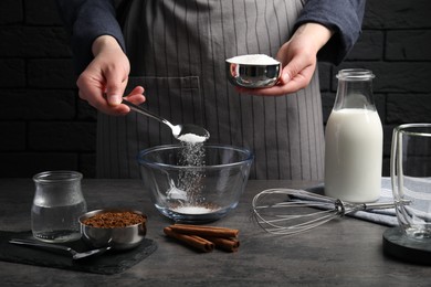 Making dalgona coffee. Woman pouring sugar into bowl at grey table, closeup