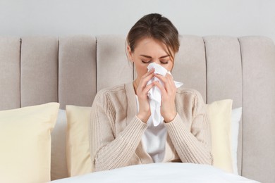 Sick woman with tissue in bed at home