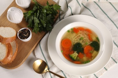 Photo of Delicious vegetable soup with noodles served on white wooden table, flat lay