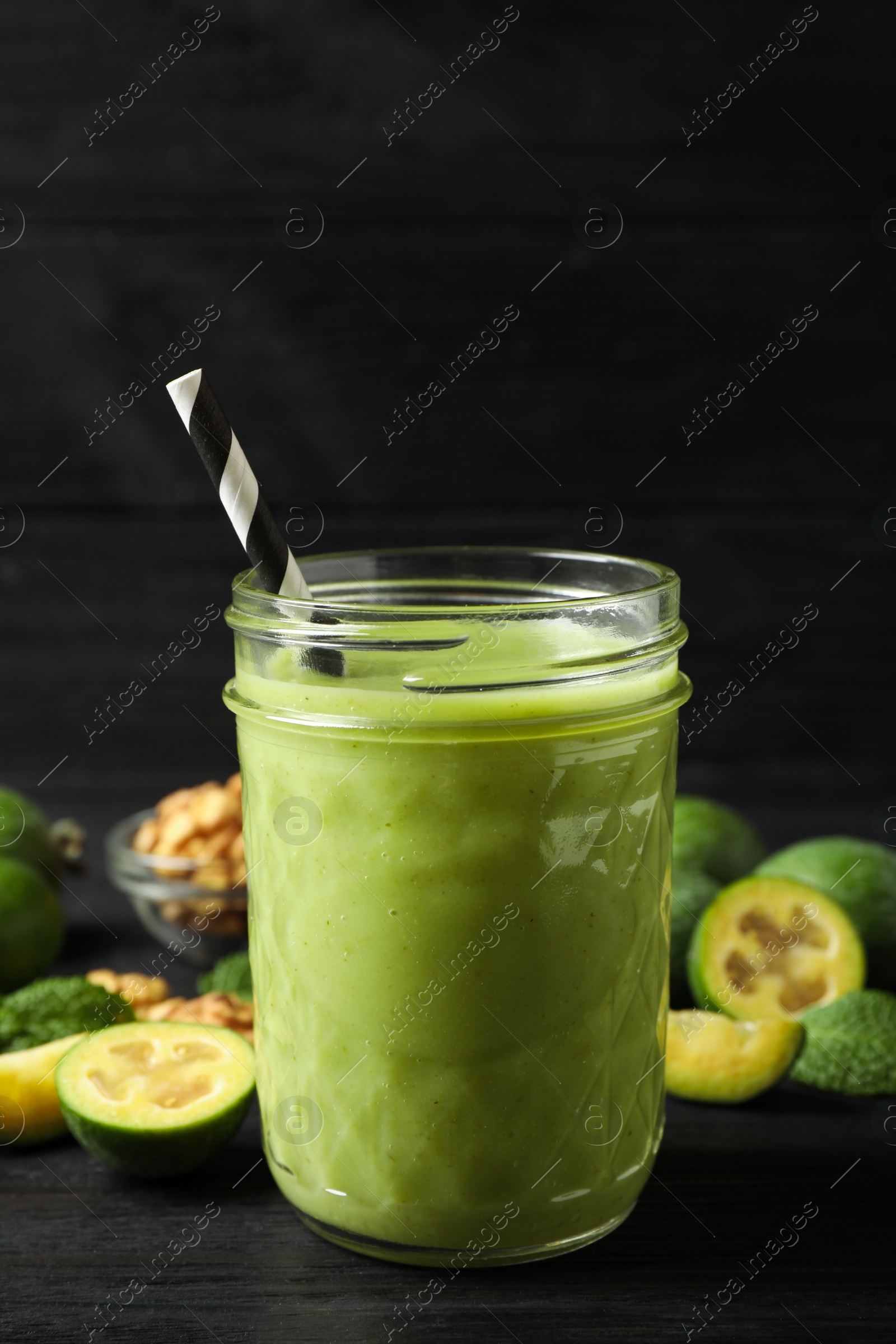 Photo of Fresh feijoa smoothie in glass on black wooden table, closeup