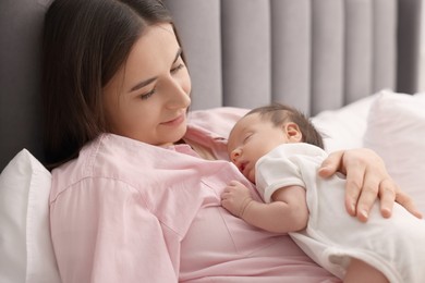 Mother with her sleeping newborn baby in bed