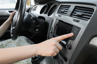 Choosing favorite radio. Woman pressing button on vehicle audio in car, closeup