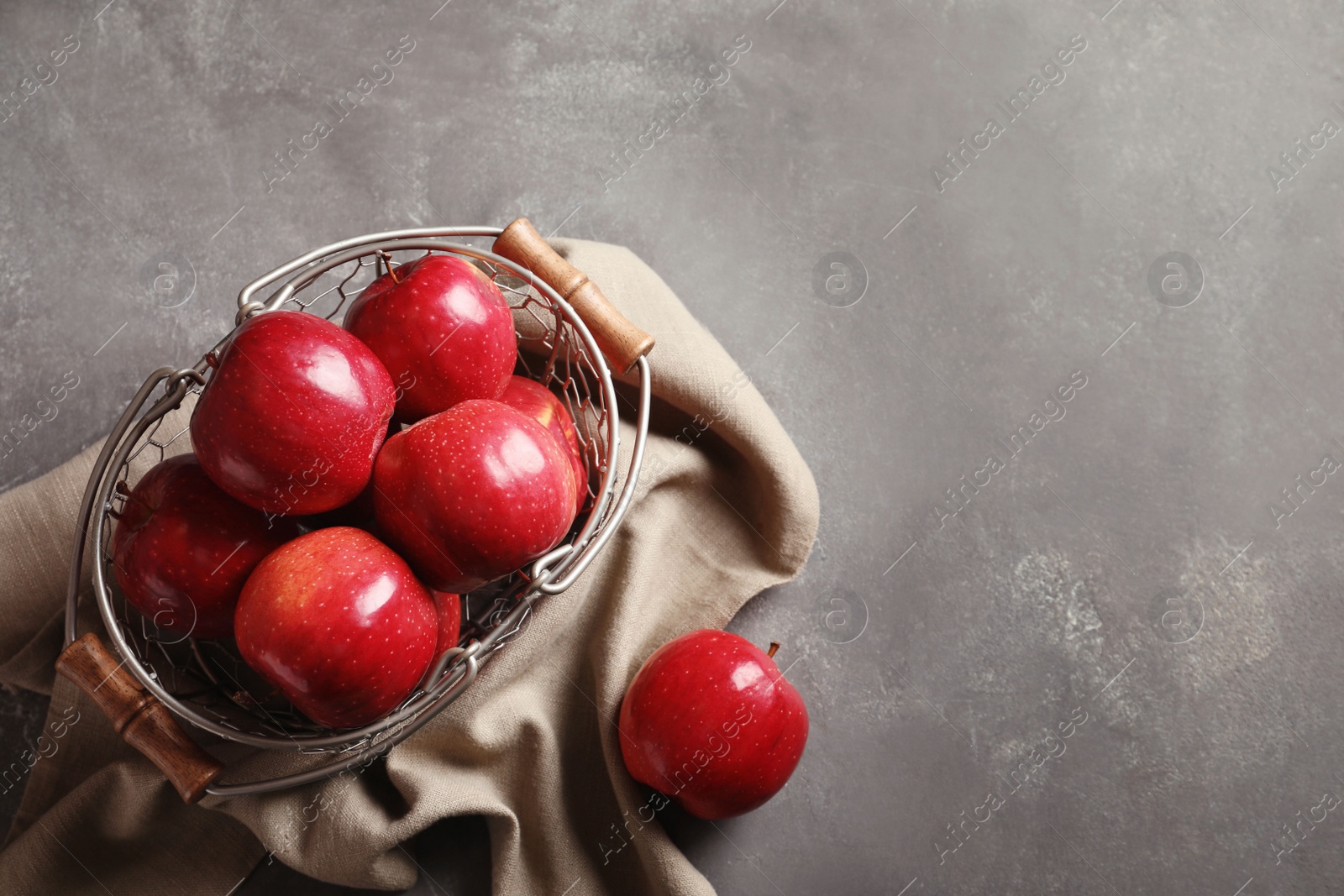 Photo of Basket with fresh ripe red apples on grey background