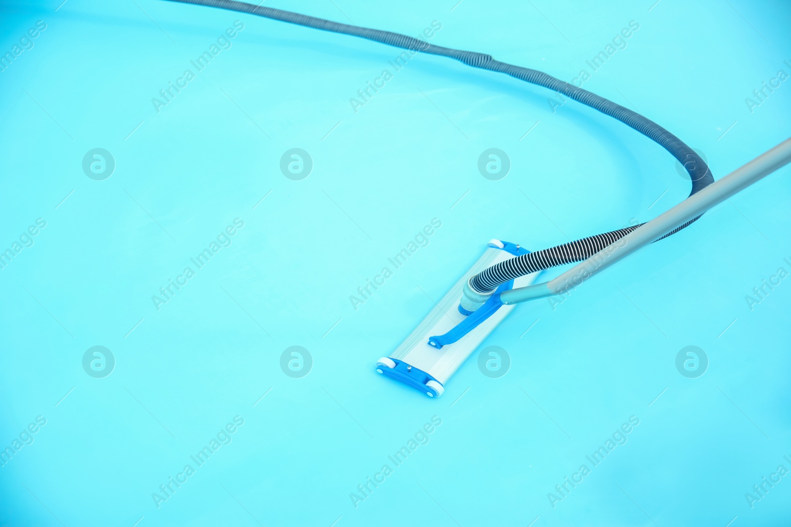 Photo of Cleaning outdoor pool with underwater vacuum, closeup