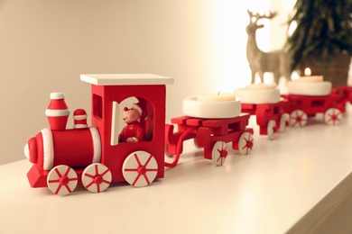 Photo of Red toy train on shelf. Christmas candle holder