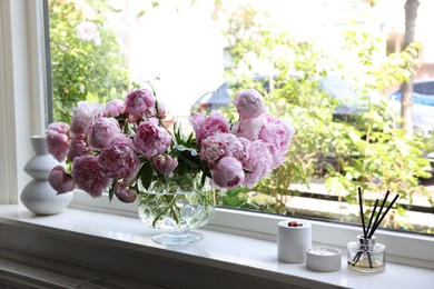 Beautiful pink peonies in vase on window sill. Interior design