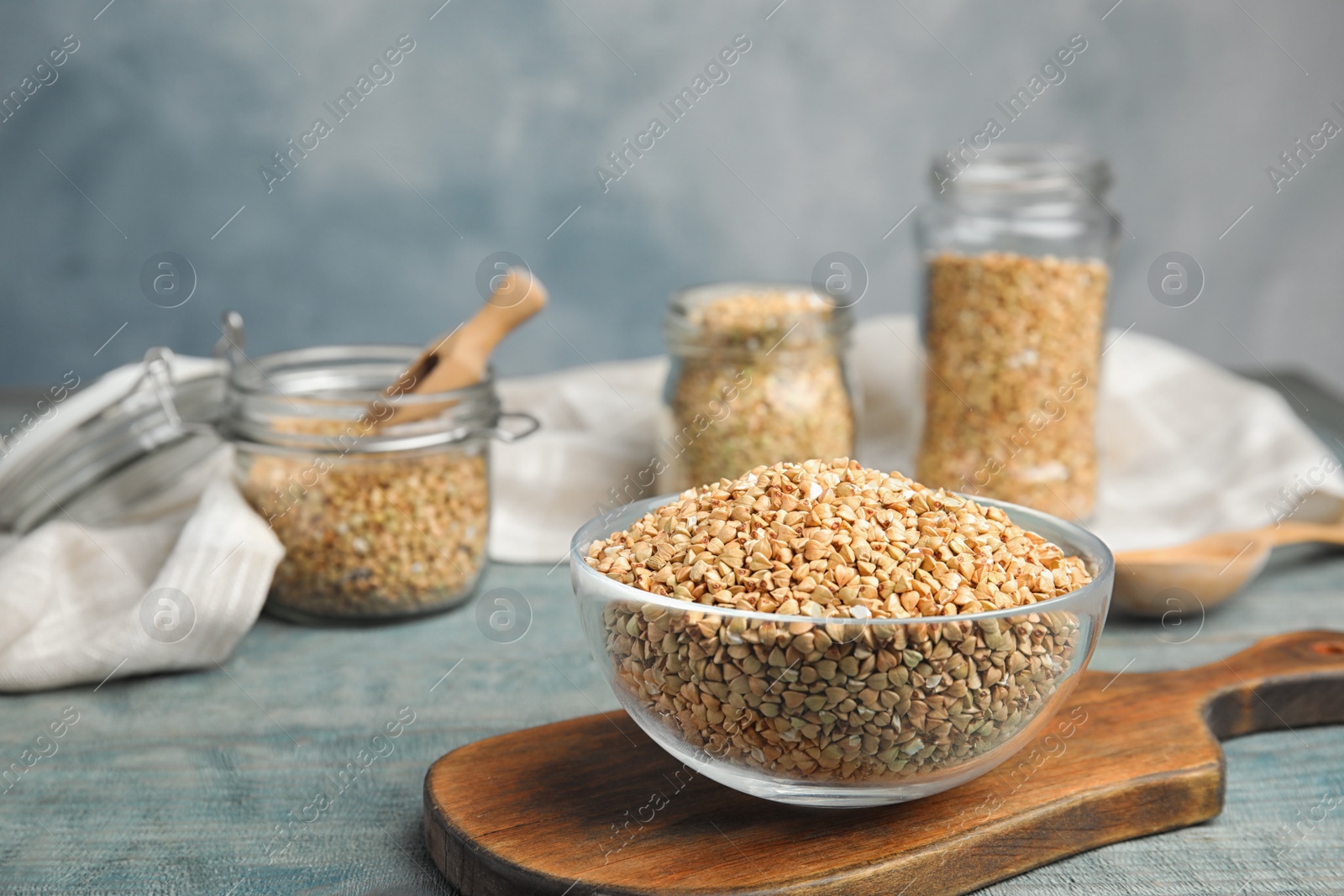 Photo of Uncooked green buckwheat grains in bowl on light blue wooden table