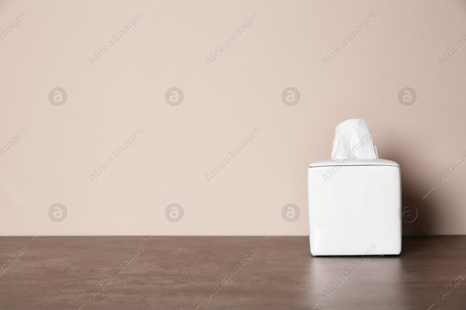 Photo of Napkin holder with paper serviettes on table against color background. Space for text