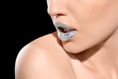 Beautiful young model with silver lips makeup on black background