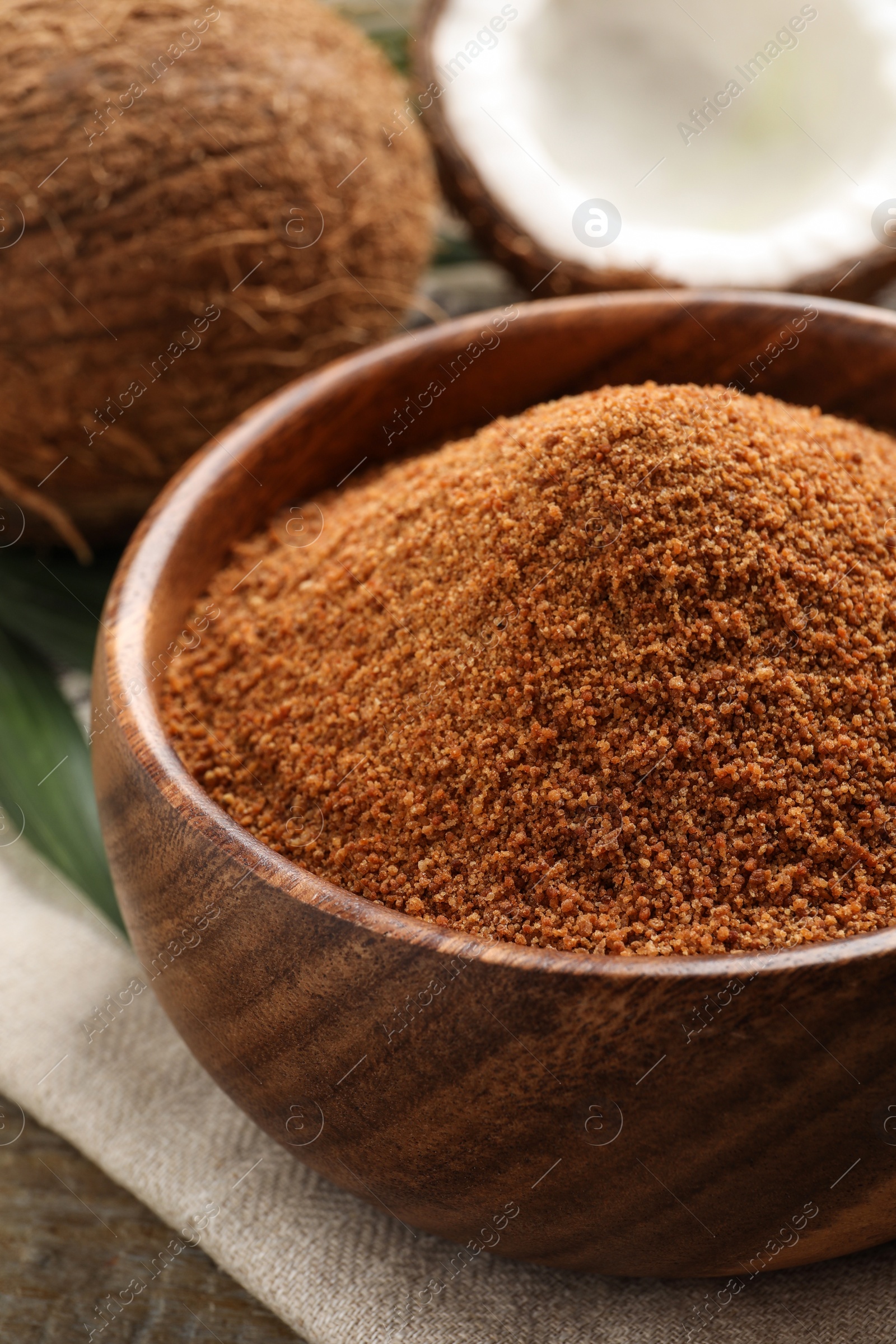 Photo of Natural coconut sugar in wooden bowl on table, closeup