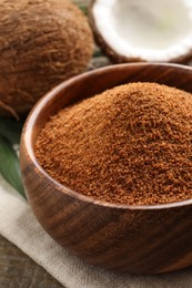 Natural coconut sugar in wooden bowl on table, closeup