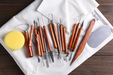 Photo of Set of different clay crafting tools on wooden table, top view